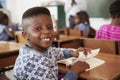 Boy at desk smiling to camera in an elementary school lesson