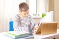 Boy with digital tablet computer writing on notebook doing homework at table. Online learning, remote education Royalty Free Stock Photo