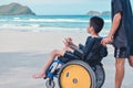Boy with disabilities on wheelchair on the beach at vacation.