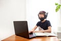 A boy in a disposable mask and headphones at home in front of a computer does his homework. Distance learning in quarantine. Royalty Free Stock Photo