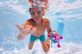 Boy dive in the pool collecting toys wear googles