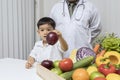 A boy and doctor happy to have healthy food. Kid learning about nutrition with doctor to choose eating fresh fruits and vegetables Royalty Free Stock Photo