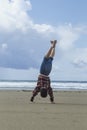 Boy does handstand on the beach.