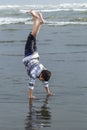 Boy does handstand in wet sand.