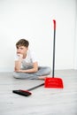 The boy does not want to clean the room. boy cleaning sitting on floor with broom. on white background teenager.