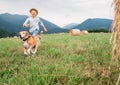 Boy and dog run together on the field with haystacks Royalty Free Stock Photo