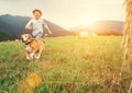 Boy and dog run together on the field with haystacks Royalty Free Stock Photo