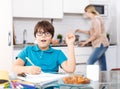 Boy doing homework, mother cooking Royalty Free Stock Photo