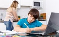 Boy doing homework, mother cooking Royalty Free Stock Photo