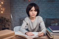 Boy is doing homework surrounded by books at night at home. Royalty Free Stock Photo