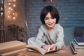 Boy is doing homework surrounded by books at night at home. Royalty Free Stock Photo