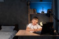 boy is doing homework using a laptop computer at his bedroom desk at night Royalty Free Stock Photo