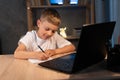 boy is doing homework using a laptop computer at his bedroom desk at night. Royalty Free Stock Photo