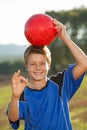 Boy doing okay sign with soccer ball.