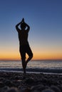 Boy doing yoga outdoors at sunrise on the beach Royalty Free Stock Photo