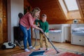 Boy with Down syndrome with his mother vacuum cleaning at home