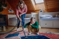 Boy with Down syndrome with his mother vacuum cleaning at home