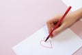 A boy draws a heart on a white sheet with a red felt-tip pen Royalty Free Stock Photo