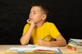 A boy dreams while sitting at a table, closing his eyes, doing homework Royalty Free Stock Photo