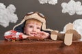 Boy dressed as an airplane pilot sit between the clouds with old suitcase and playing with handmade plane Royalty Free Stock Photo