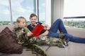 Boy dressed in dinosaur costume reading picture book with father on sofa bed at home