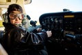 Boy dressed in large pilot jacket, headset and aviator glasses, sitting in cockpit