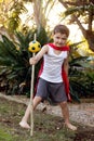 A boy dressed in a red cape holding a make-believe magic staff