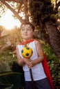A boy dressed in a red cape holding a make-believe magic staff