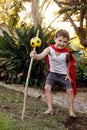 A boy dressed in a red cape holding a make-believe magic staff