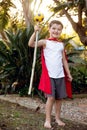 A boy dressed in a red cape holding a make-believe magic staff