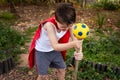 A boy dressed in a red cape holding a make-believe magic staff