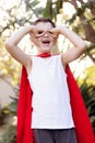 A boy dressed up as a superhero.He is wearing a red cape.