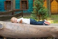 A Boy Dressed In A White T-shirt And Jeans Is Playing In The Park. He Lay Down On A Bench Made Of A Huge Tree Trunk, He