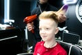 The boy dried hair with a hairdryer at the barbershop