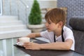 Boy is drinking coffee in cafe. Child in restaurant. Independent teenager Royalty Free Stock Photo