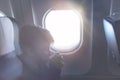 A boy drinking from paper cup sitting near airplane window during air flight. Food served on board Royalty Free Stock Photo