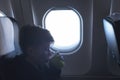 A boy drinking from paper cup sitting near airplane window during air flight. Food served on board Royalty Free Stock Photo