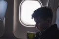 A boy drinking from paper cup sitting near airplane window during air flight. Food served on board Royalty Free Stock Photo
