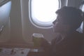 A boy drinking from paper cup sitting near airplane window during air flight. Food served on board Royalty Free Stock Photo