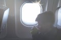 A boy drinking from paper cup sitting near airplane window during air flight. Food served on board Royalty Free Stock Photo