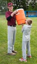 Older brother helping younger brother get a drink after a baseball game