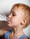 The boy is drinking water from bottle