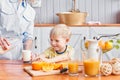 The boy drinks milk from a glass. Mother and son are smiling while having a breakfast in kitchen. Mom is pouring milk Royalty Free Stock Photo