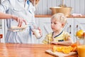 The boy drinks milk from a glass. Mother and son are smiling while having a breakfast in kitchen. Mom is pouring milk Royalty Free Stock Photo