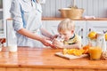 The boy drinks milk from a glass. Mother and son are smiling while having a breakfast in kitchen. Mom is pouring milk Royalty Free Stock Photo