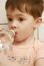 The boy drinks water from a bo