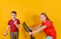 A boy with dumbbells and a girl sitting on an exercise bike, sports positive children on a yellow background