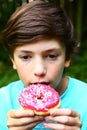 Boy eat doughnut with pink strawberry Royalty Free Stock Photo