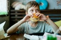 Boy eating a big burger with a cutlet. Hamburger in the hands of a child. Delicious and satisfying chicken cutlet burger. Royalty Free Stock Photo