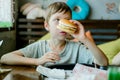 Boy eating a big burger with a cutlet. Hamburger in the hands of a child. Delicious and satisfying chicken cutlet burger.